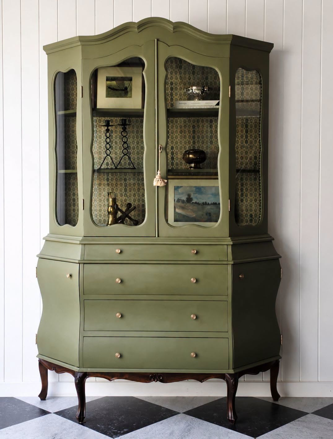 Riverbank Green glass-front cabinet against white panelling above a black-and-white tiled floor.